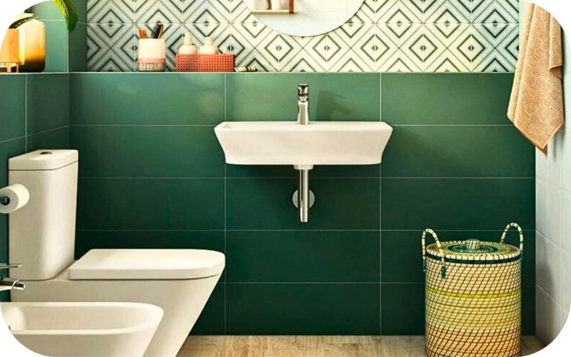 Kupatilo sa zelenim zidnim pločicama i geometrijskim dezenom iznad umivaonika
