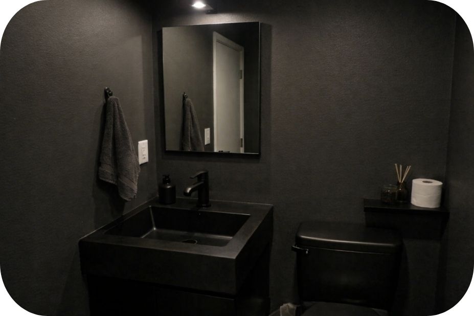 Tamno kupatilo sa crnim lavabo elementima i slabim osvetljenjem koje vizuelno zatvara prostor